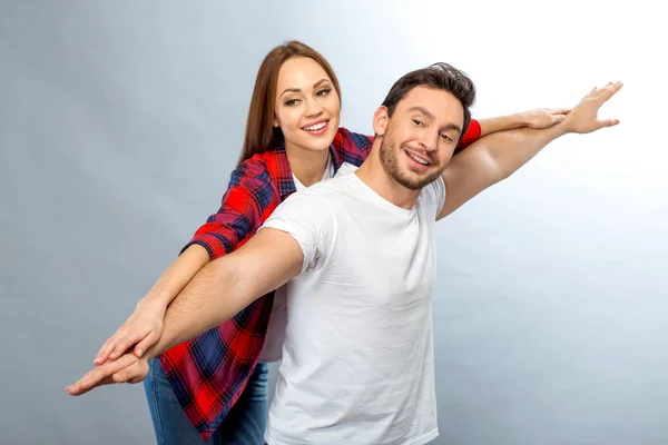 Casal vivaz se divertindo no fundo cinza — Fotografia de Stock