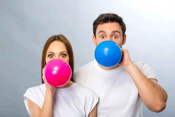 Joyeux jeune couple soufflant des ballons — Photo