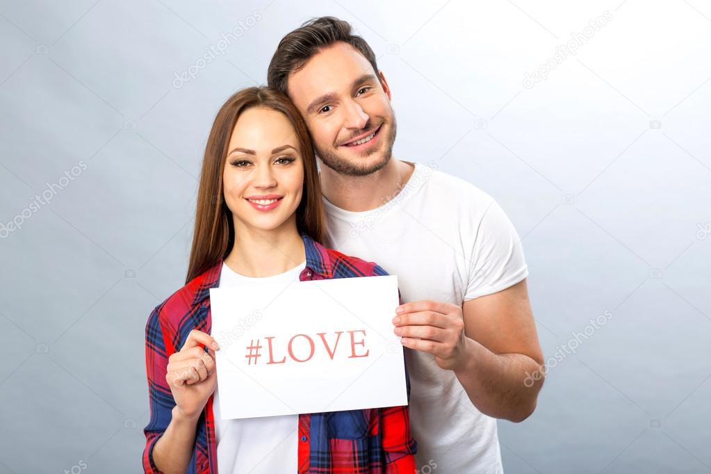 Nice young couple holding sheet of paper