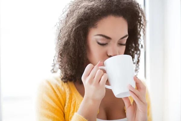 Pleasant mulatto woman drinking tea — Stock Photo, Image