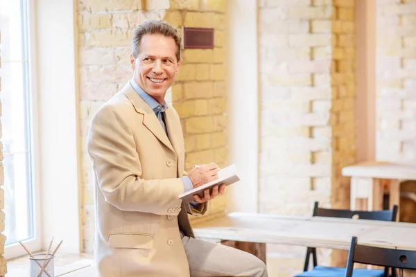 Fröhlicher Mann macht sich Notizen — Stockfoto