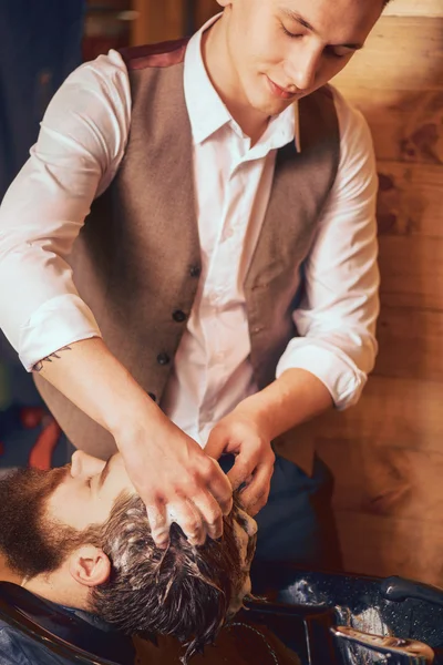 Professional barber washing head of bearded man — Stock Photo, Image