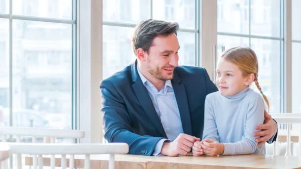 Позитивный отец и его маленькая дочь сидят в кафе — стоковое видео