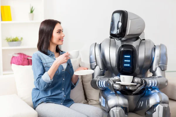Positive girl resting on the couch with robot — Stock Photo, Image