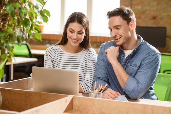 Encantados colegas sonrientes sentados a la mesa — Foto de Stock