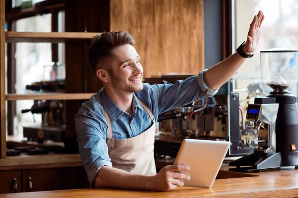 Barista menyenangkan menggunakan tablet duduk di meja — Stok Foto