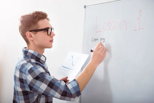 Concentrated male student writing on the blackboard — Stock Photo, Image