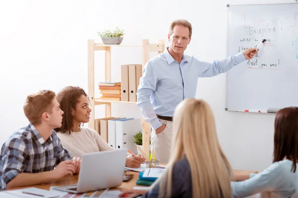 Junge fröhliche Menschen sitzen am Tisch — Stockfoto