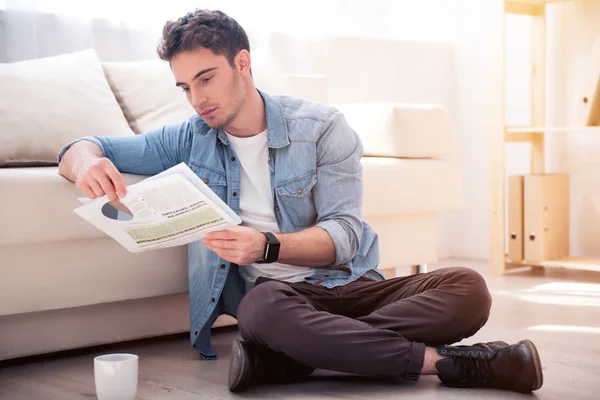 Angenehmer ernster Mann auf dem Fußboden sitzend — Stockfoto