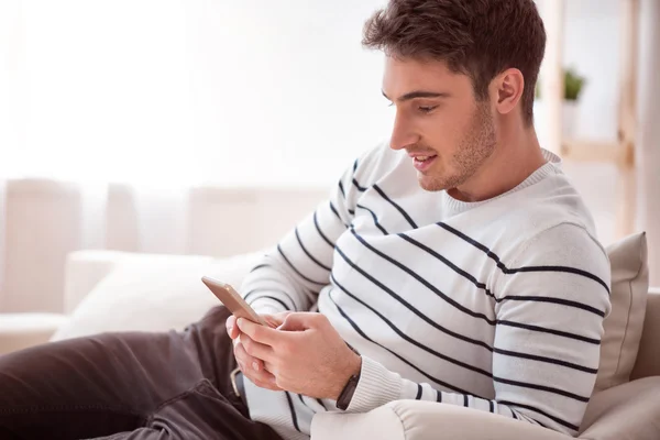 Angenehm entzückter Mann sitzt auf dem Sofa — Stockfoto