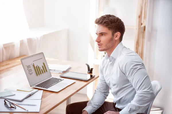 Agradable hombre concentrado sentado a la mesa — Foto de Stock