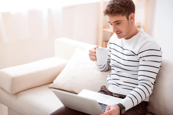 Erfreut schöner Mann sitzt auf dem Sofa — Stockfoto