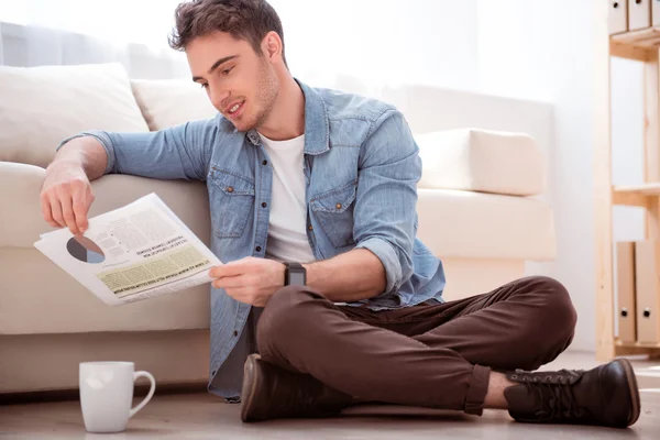 Angenehm lächelnder Mann auf dem Boden sitzend — Stockfoto