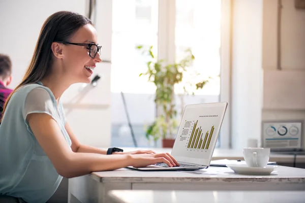 Överlycklig kvinna som arbetar på den bärbara datorn — Stockfoto