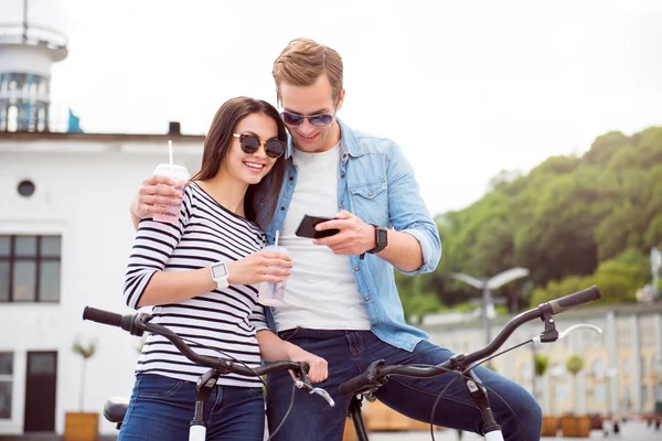 Пара дивиться на смартфон і п'є — стокове фото