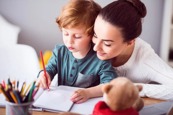 Mère regardant un enfant dessiner une image — Photo