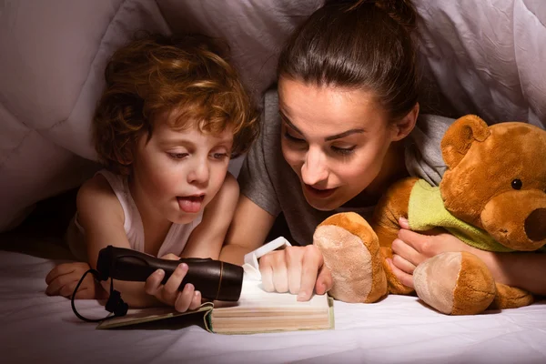 Matka i dziecko czytanie książki pod koc — Zdjęcie stockowe