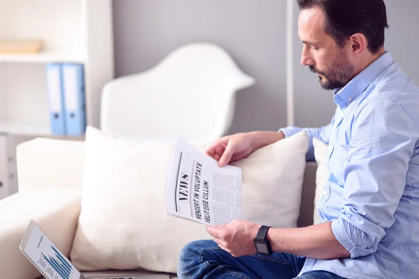 Mann liest Zeitung vor Laptop — Stockfoto