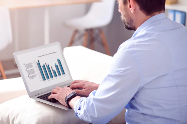 Man working on laptop with diagrams — Stock Photo, Image