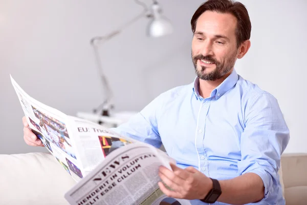 Uomo sorridente che legge un giornale — Foto Stock