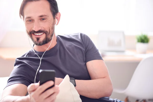 Man with earphones looking at phone — Stock Photo, Image