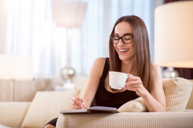 Woman drinking coffee and taking notes