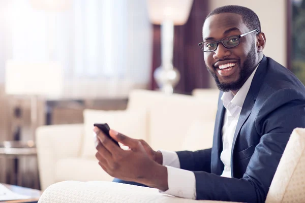 Hombre mirando a la cámara y sosteniendo el teléfono — Foto de Stock