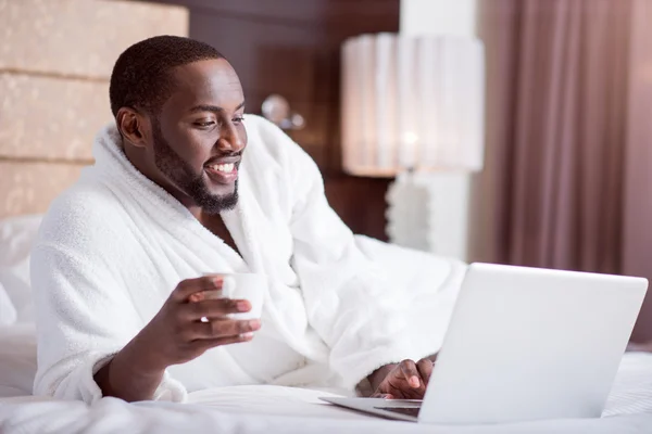 Uomo che si rilassa sul letto con laptop — Foto Stock