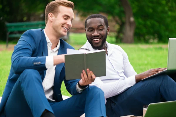 Des collègues positifs assis sur l'herbe — Photo