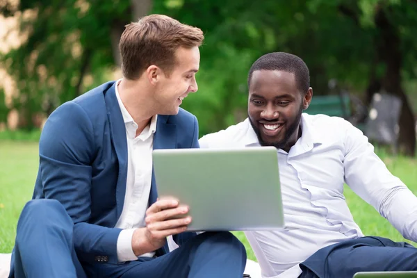 Confrères joyeux en utilisant un ordinateur portable sur l'herbe — Photo