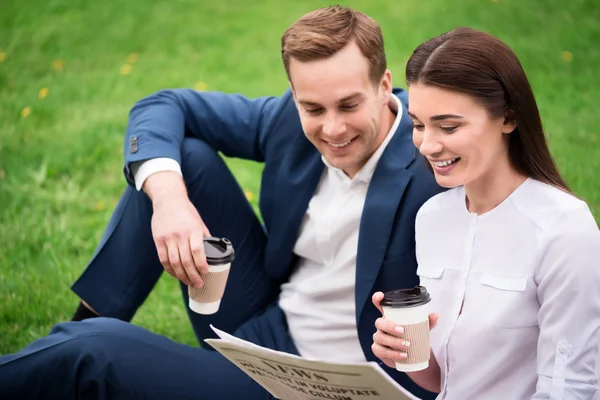 Positive colleagues drinking coffee on the grass — Stock Photo, Image