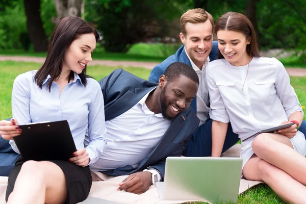 Vrolijke collega's zittend op het gras — Stockfoto