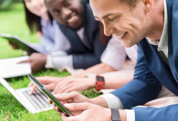 Vrolijke collega's zittend op het gras — Stockfoto