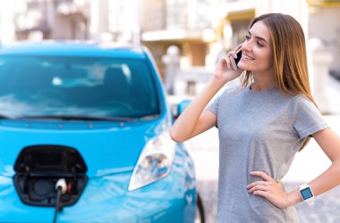 Kadın araba şarj ederken Smartphone'da söz