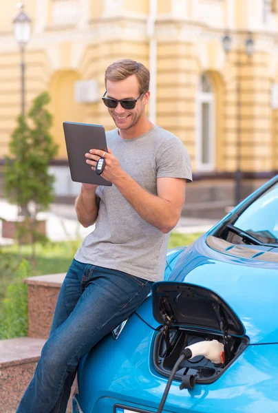 Hombre usando la tableta cerca de eco coche —  Fotos de Stock