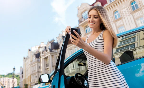 Frau schaut auf Handy in der Nähe von Auto — Stockfoto