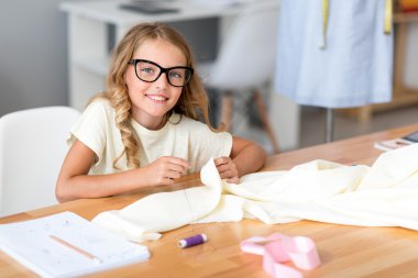 Küçük kız terzilik ve kamera bakıyor