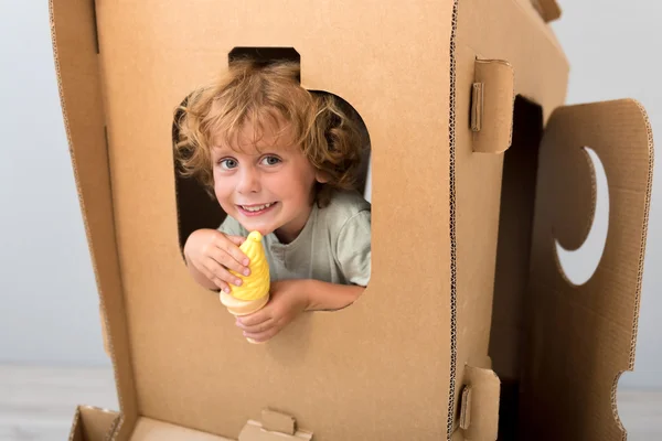 Cute boy sitting in carton rocket — Stock Photo, Image