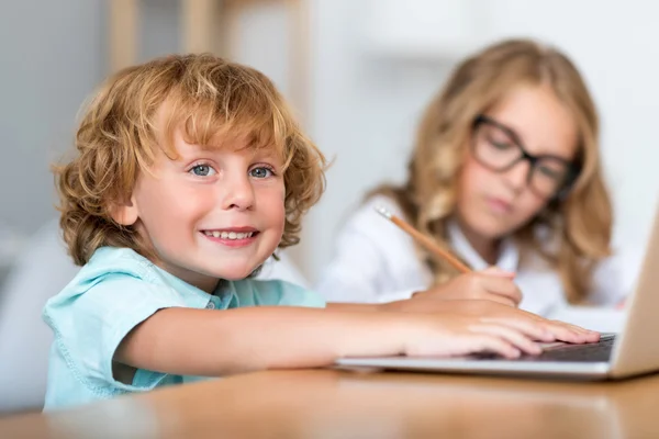 Sonriente niño trabajando en el ordenador portátil — Foto de Stock