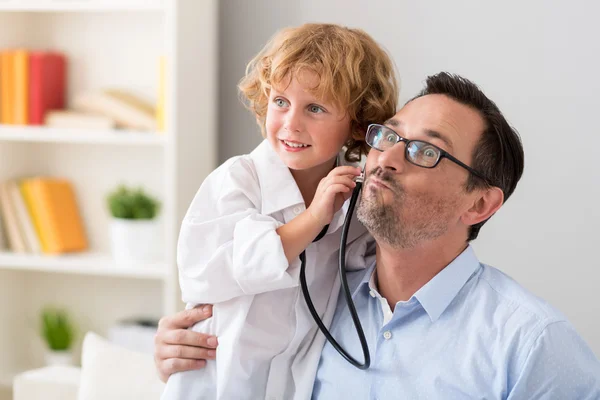 Weinig onderzoekende vader van de jongen met de stethoscoop — Stockfoto