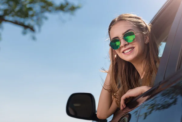 Mujer sonriente positiva mirando hacia fuera del coche — Foto de Stock