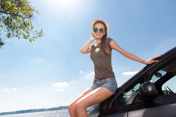 Freudige Frau lehnt sich ans Auto — Stockfoto