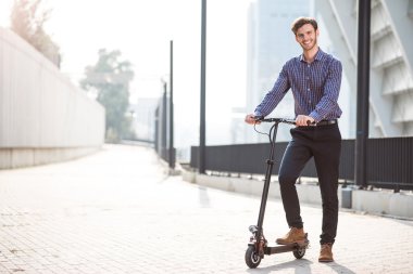 Gülümseyen adam bir tekme scooter sürme