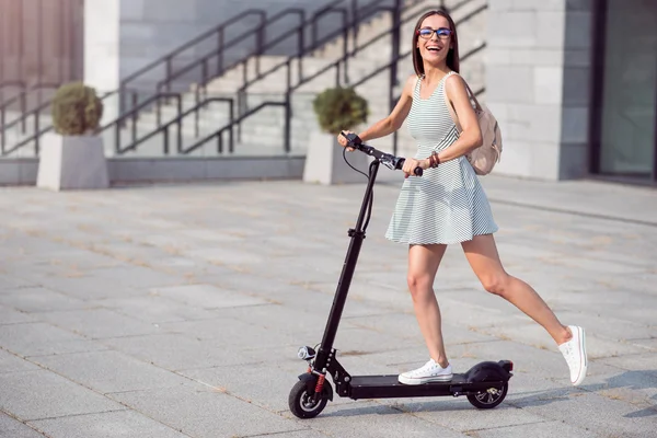 Mujer alegre montando un patinete scooter —  Fotos de Stock