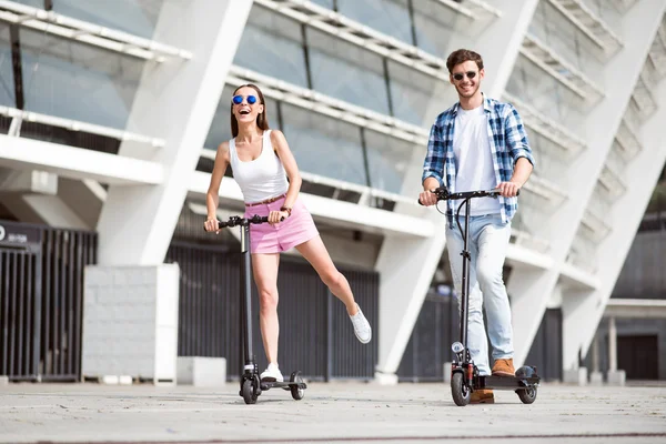 Amigos alegres montando uma scooter pontapé. — Fotografia de Stock