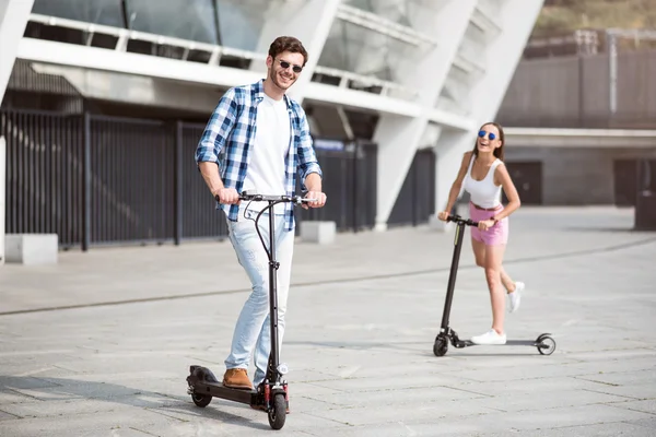 Joyful friends riding kick scooters Stock Image