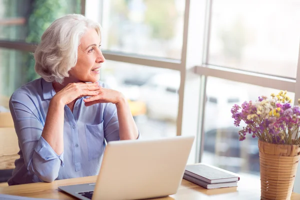 Agradable encantado mujer mayor sentada a la mesa — Foto de Stock