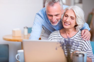 Çift gülümseyen ve dizüstü bilgisayar kullanarak