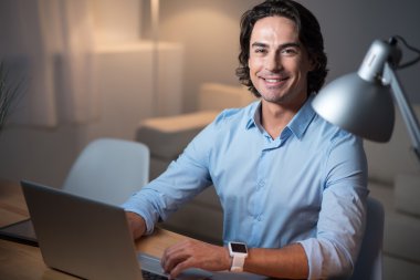 Gülümseyen yakışıklı üstünde laptop çalışma.