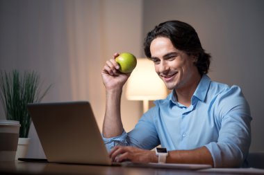 Dizüstü bilgisayarda çalışan iyi görünümlü genç adam.